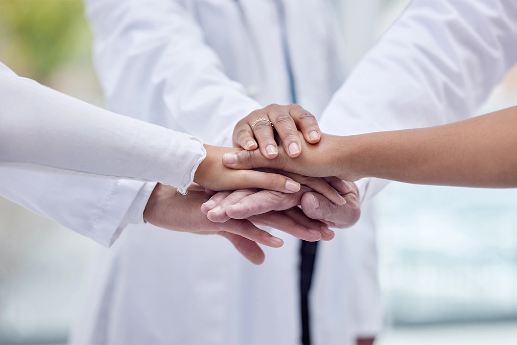 Patients and doctors stacking hands in center