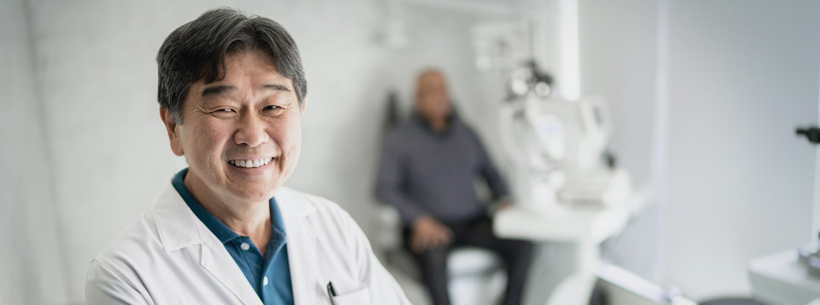 physician smiling with patient in the background