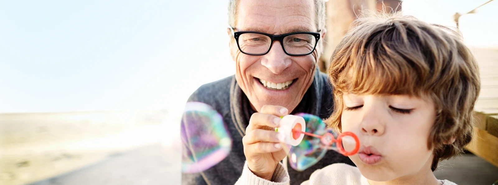 older man and a young boy blowing bubbles outside