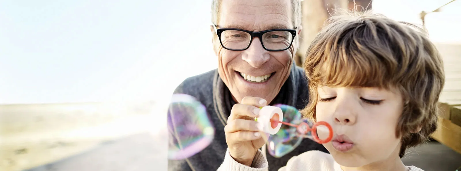 child blowing bubbles with older man